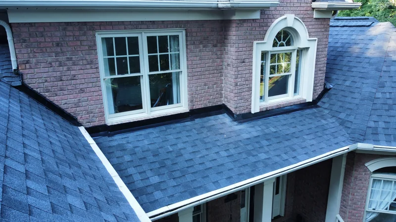 Black flashing where gray shingles meet a brick dormer