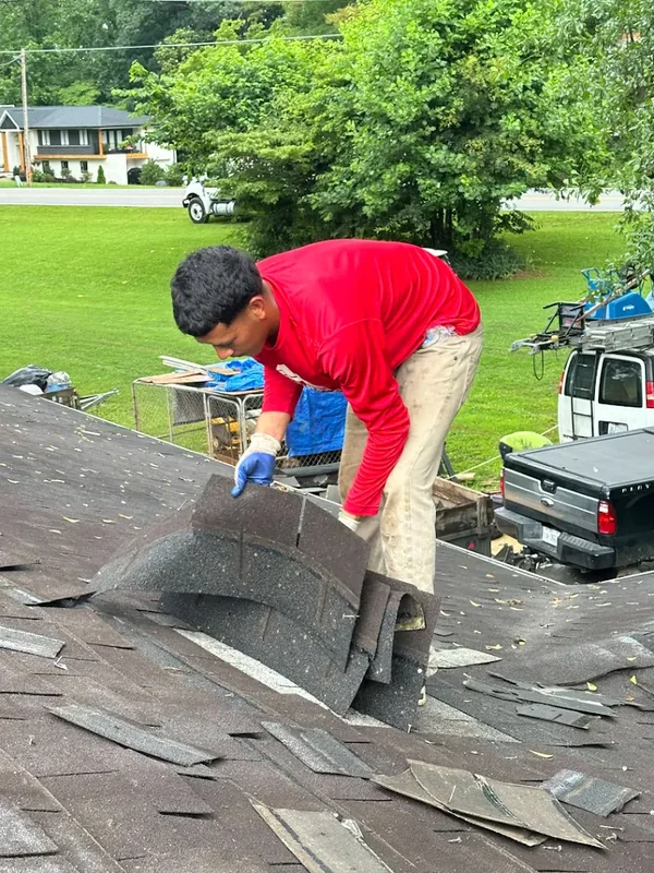 Crew member removing old roof shingles