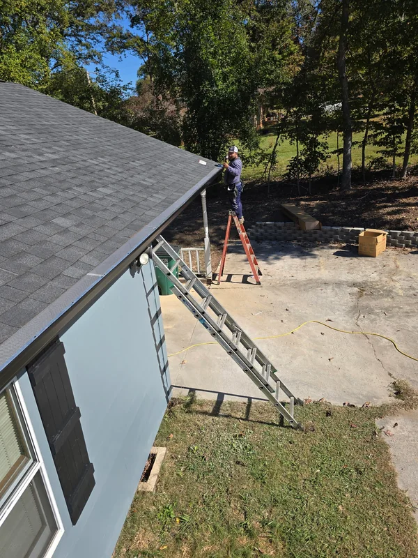 Triumph Roofing crew member installing gutter covers at the roof edge