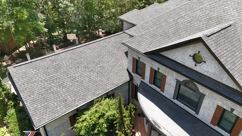 Aerial view of gray shingle roofs and gables on a white brick home